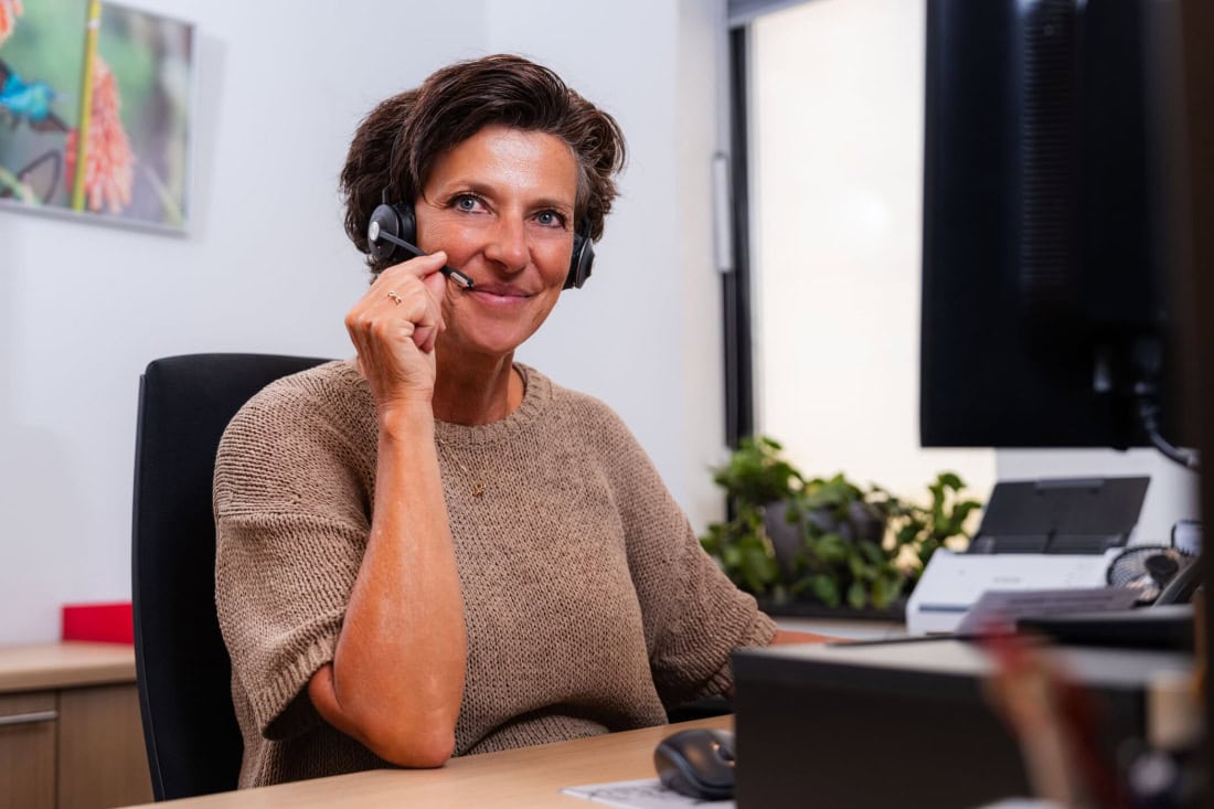 Care assistant with headset at computer, customer service or medical support.