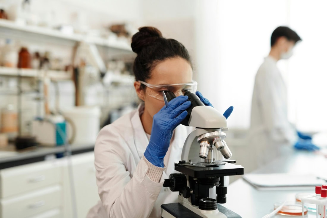 Scientist examines with microscope in lab for HPV self-test.