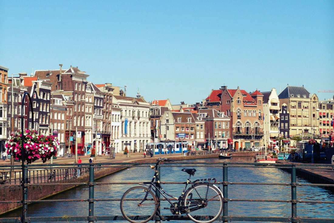 Cyclist by the canals in a historic Dutch city, colourful buildings and bridges.